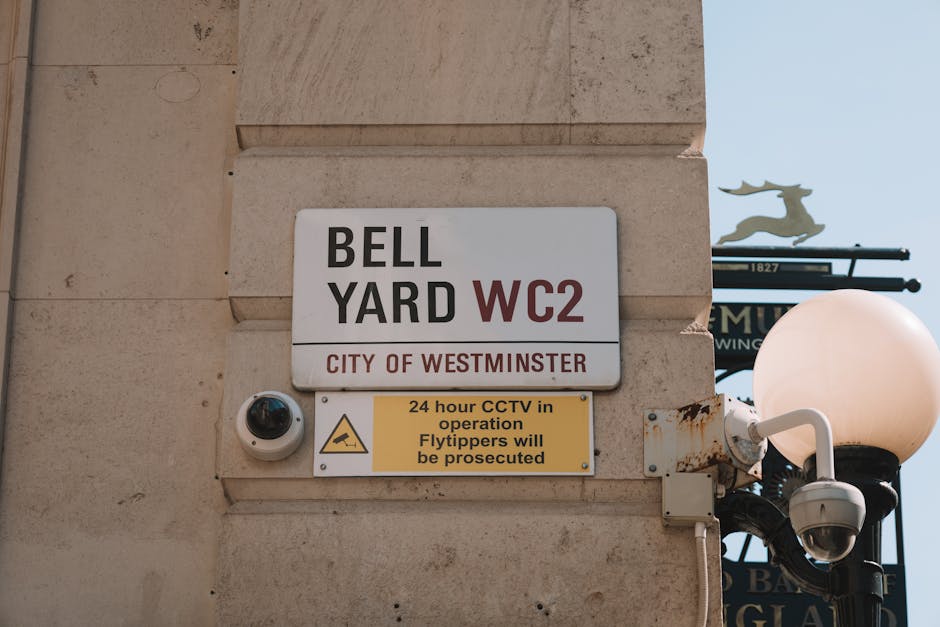Close-up view of the exterior wall of a building in Belgravia, Westminster, displaying a white rectangular street sign with black and red lettering indicating 'BELL YARD WC2' under the jurisdiction of