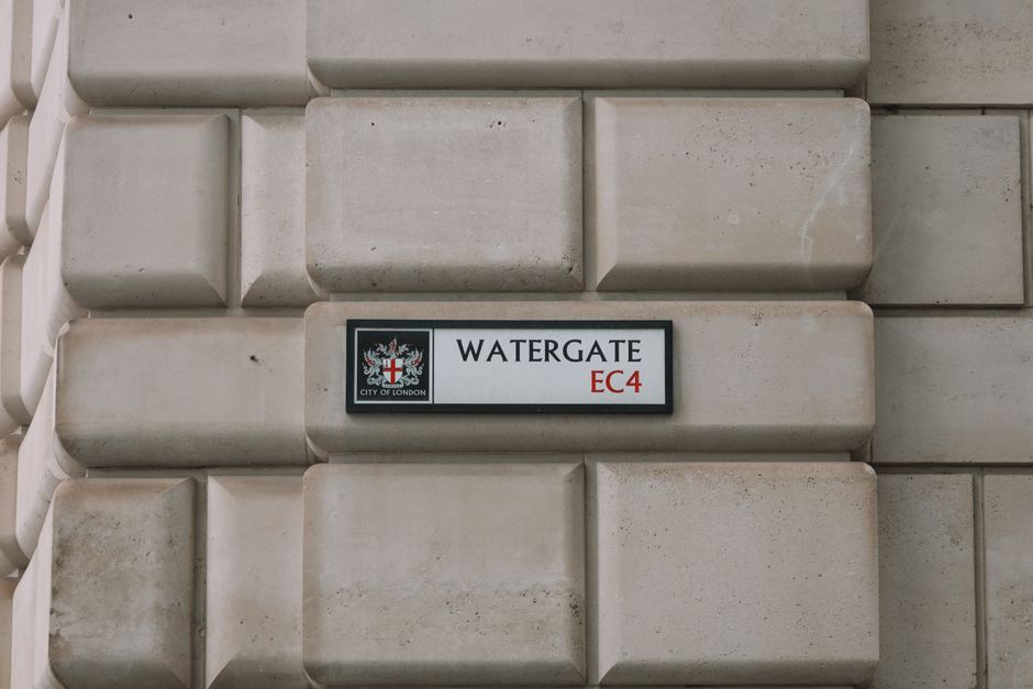 Close-up view of the exterior wall of a building in Belgravia, Westminster, displaying a white rectangular street sign with black and red lettering indicating 'BELL YARD WC2' under the jurisdiction of